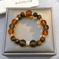 Macro shot of tiger eye beads and amber stones on a grey jewelry display box - Brown Cat's Eye and Amber Bead Bracelet Style (6356)