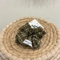 Nahaufnahme von dunkelgrünem Karo-Haargummi mit weißem Markenlabel auf Flechthintergrund - Grün Weiß Rosa Kariertes Scrunchie