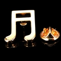 Macro shot of a golden eighth note music brooch with a butterfly clasp on black background - Gold Musical Note