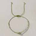 Detalle de pulsera trenzada verde hecha a mano con piedra pulida y adornos en tono dorado - Ojo de Gato Turquesa Trenzado