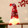 Nahaufnahme eines leuchtenden Weihnachtswichtels mit Sternhut und LED-Bartbeleuchtung - Sitzende Haltung / Rot