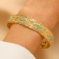 Gold open cuff bracelet with turquoise stones and textured hammered finish on wrist - Hammered Eye Rhinestone Bracelet (DZ-203)