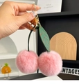 Détail de porte-clés cerise en fourrure de lapin rose avec feuille en cuir et fermoir doré - Rose