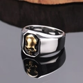Punk style skull ring for men in silver and gold tone stainless steel on dark surface - US 7 / Gold & Silver