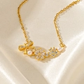 Vue détaillée du pendentif papillon doré orné de fleurs, de cristaux et de perles blanches - Fleur en Zircon Blanc (F208)