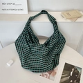 Detail der grün-schwarzen karierten Canvas Hobo-Bag Textur auf einem Schreibtisch - Jacquard Grünes Gitter