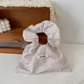 Close-up of floral canvas handbag with ruffled handle and branded Sozakka woven label - Twill Flowers