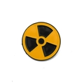 Dettaglio della spilla rotonda in metallo giallo e nero con simbolo radiazioni - Segnale di Radiazione Nucleare