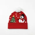 Red Christmas knit beanie featuring a white pom-pom, green tree, and snowman pattern - Tree Snowman