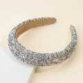 Detail of padded headband with colorful rhinestones and white pearls on beige background - Colorful