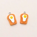 Detailed macro view of two resin toast and fried egg pendants with metal rings - Egg Toast