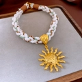 Braided white necklace with a gold sun pendant featuring a hammered metal texture - Gold Sun Pendant Woven Necklace