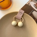 Cute beige children hair tie with two smooth cream-colored balls on a ceramic plate - Cream