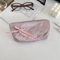 Close-up of pink glossy quilted pencil case with bow detail on white desk setup - Matte Flesh Pink
