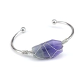 Close-up of handmade silver wire wrapped natural raw purple crystal on an open cuff bracelet - Fluorite