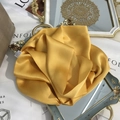 Detail of a bright yellow 100% mulberry silk scarf folded into an elegant rose shape - 15x150cm / Sunny Yellow