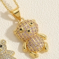 Goldene Bärenhalskette mit violetten Zirkoniasteinen auf cremefarbenem Hintergrund - Lila Zirkonia Bär (XL2643-1)