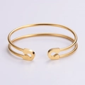 Detalle de brazalete abierto de doble carril en acero inoxidable con acabado en oro cálido - Dorado