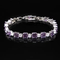 Detail of tennis bracelet with purple square gems and round crystals on black background - Purple