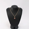 Close-up of a festive Christmas tree pendant with red and green enamel on a gold chain - Christmas Tree Type B
