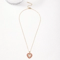 Collier doré avec pendentif cœur orné de zircons rouges et blancs sur fond blanc - Zircone Rouge Orangé