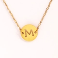 Vue détaillée d'un collier doré en acier inoxydable avec pendentif rond lettre M ajourée - Lettre M