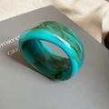 Detail of emerald green resin bangle with dark marble texture on minimalist grey box - Emerald Green Marble
