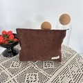 Detail of a brown corduroy cosmetic bag on a white lace tablecloth with lifestyle props - Brown