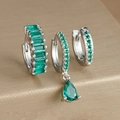 Macro detail of emerald green stone earrings set on a golden brushed jewelry box - Three-Piece Set / Silver-Green Zirconia