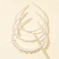 Detailed view of three pearl headbands with various faux pearl sizes on beige background - Style A Pearl Headband 3-Piece Set