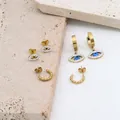 Hip-Hop-Ohrstecker-Set Böser Blick mit Zirkon-Steinen in Gold-Finish auf Steinfläche - Gold