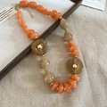 Detail of chunky resin beads in orange and beige with gold spacers on textured background - Orange Necklace