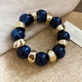 Dettaglio di perle in acrilico marmorizzato blu e distanziatori dorati su un bracciale - Blu - Oro
