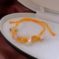 Close-up of a woven orange and yellow bracelet with resin flower charms in a gift box - Orange-Yellow Two-Color Woven Flower