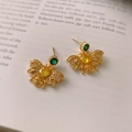 Macro detail of golden bee earrings with yellow stones and crystals on a book - Golden Bee Zirconia Earrings (Silver Needle)