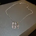 Silver zircon fleur-de-lis and cross pendant necklace with sparkling stones on grey box - Silver Cross Necklace
