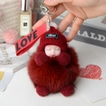 Detail of sleeping baby plush keychain with burgundy faux fur pompom and metal clip - Burgundy