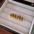 Detailed macro view of golden alphabet stud earrings with black enamel inlay in a box - Black