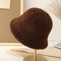 Close-up of thick dark brown plush bucket hat texture on a minimalist gold stand - Coffee