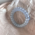 Detail of light blue translucent spiral hair tie with a flexible telephone cord design - Blue Spiral