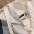 Detalle del bolso tote de lona gruesa con texto negro China y correas de hombro anchas - Blanco lechoso