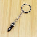 Polished hexagonal black crystal pendant keychain with silver metal ring on wood - Obsidian