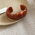 Detail of amber marble acrylic bangle on ceramic tray with elegant textured fabric - Adjustable Size / Orange