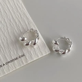Makro-Detail von silbernen gedrehten Creolen mit polierter Metalloberfläche - Echt Versilbert / Silber