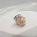 Detailed close-up of a pink enamel pig charm with silver bow on a white display pedestal - Style G (Pig)