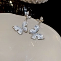 Dettaglio ravvicinato di orecchini a farfalla con texture di pietre su un piatto bianco - No.6 Orecchini a Bottone a Farfalla in Cristallo e Zircone con Perno in Argento