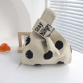 Detailed close-up of beige knitted tote bag featuring black polka dots and slogan strap - Letters On A White Background With Black Dots