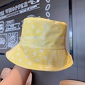 Detail view of yellow paisley bucket hat made of cotton held by hand on street style wall - One Size / Yellow