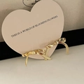 Elegant golden bow-shaped stud earrings in vintage style on a black velvet stand - Metal Ribbon Bow