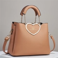 Close-up of the heart-shaped metal buckle and lychee texture on the khaki leather handbag - Pink
